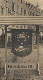 1915 Mit dem Wappen der Stadt Wilster versehenes Nagelbild "Kriegswahrzeichen Wilster"; am 26.09.1915 feierlich auf dem Platz am Colosseum aufgestellt. 