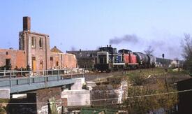 1988 - Ein Güterzug passiert in Rumfleth bei Wilster die Ruinen der am 14.10.1987 abgebrannten Möbelhandlung Grünhagen